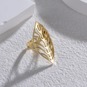 Gold leaf-shaped open ring with intricate cutout patterns on a white stone background