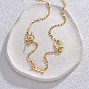 Minimalist gold geometric necklace with pig nose links and OT buckle on white stone tray