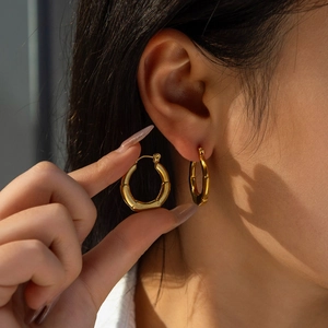 Détail de créoles dorées à texture bambou portées pour montrer le style et la taille