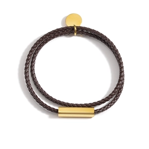 Détail du bracelet double en cuir marron avec breloque et fermoir en métal doré poli