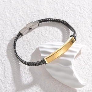 Close-up of industrial style black mesh chain bracelet with gold-plated geometric plate