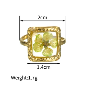 Détail de la bague carrée en résine de 2 cm avec fleurs séchées et texture martelée