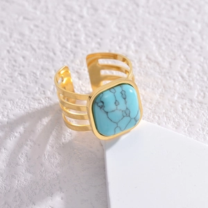 Gold stainless steel open ring featuring a square turquoise stone on a white display