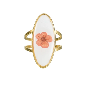Détail macro d'une bague ovale dorée ornée d'une véritable fleur séchée orange en résine