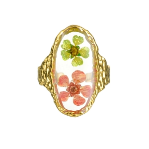 Gros plan sur la bague ovale artisanale avec de vraies fleurs séchées et cadre doré