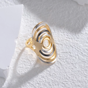 Minimalist multi-layer hollowed-out ring in gold and silver finish on a textured stone