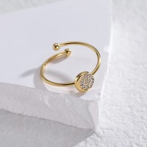 Adjustable gold open ring with round pave zircon setting on a white marble stand