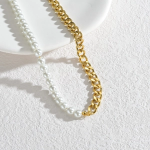 Collier minimaliste avec perles et chaîne dorée présenté sur une surface en pierre blanche