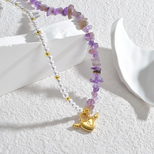 Fashion necklace featuring white pearls, purple stones and golden winged heart lock pendant