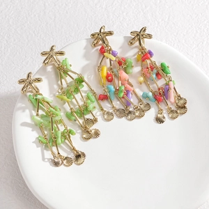 Starfish beaded tassel earrings with gold sea shells and green coral beads on a white tray
