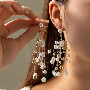 Elegant beaded tassel earrings featuring white pearls and golden beads in a cascading star design
