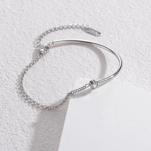Minimalist silver stainless steel bracelet with zircon inlay on white geometric stand