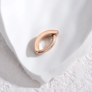 Minimalist rose gold stainless steel navel ring with a matte finish on a stone tray