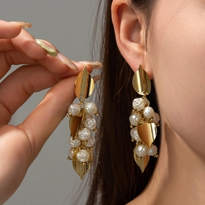 Close-up of elegant gold tassel earrings with white resin rose beads on model ear