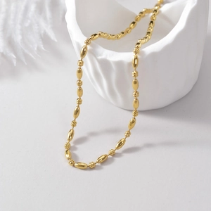 Chic gold stainless steel bead necklace displayed on a minimalist artistic background