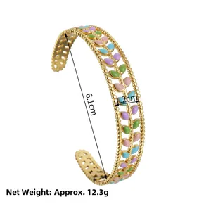 Detail view of gold stainless steel cuff bracelet featuring colorful enamel leaf patterns