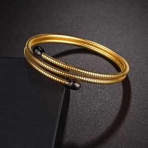 Detail of gold multi-layer spring bracelet with black bullet charms on dark display