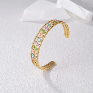 Detail of gold branch bangle with colorful enamel leaves and fine beaded edges