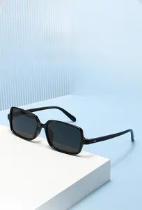 Detail of black square sunglasses with silver rivet accents on a minimalist white stand