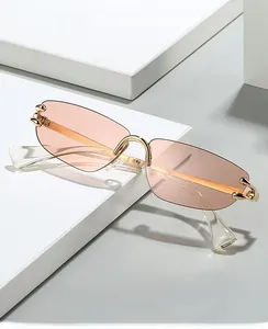 Detail of rimless sunglasses with pink lenses and gold claw-shaped metal accents