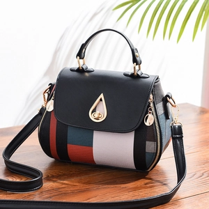 Chic multi-color patchwork crossbody shell bag with elegant gold teardrop lock on wood