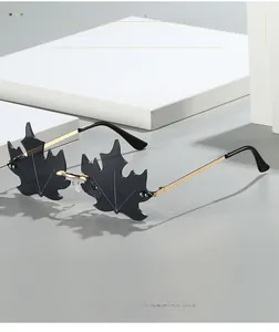 Detail of creative maple leaf shaped sunglasses with gold metal temples and grey lenses