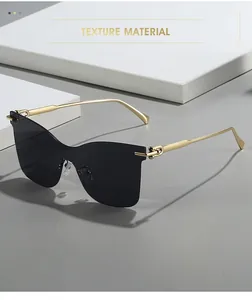Detail of golden loop hinges and dark lenses on rimless cat-eye sunglasses with metal temples