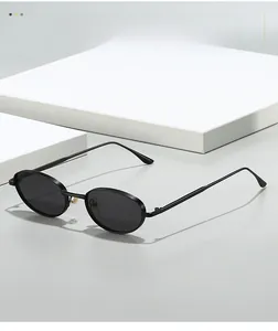 Gros plan sur les lunettes de soleil ovales noires en métal avec verres foncés sur présentoir