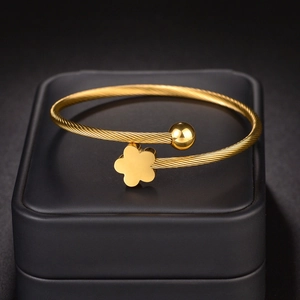 Gold stainless steel twisted cable bangle featuring a floral charm and polished metal ball
