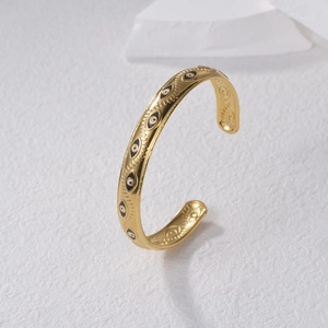 Minimalist gold evil eye open cuff bracelet with black and white enamel pattern detail