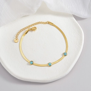 Detail of gold snake chain bracelet with three turquoise stones in stainless steel