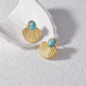 Détail de boucles d'oreilles vintage en éventail doré avec turquoise ovale et motifs radiaux