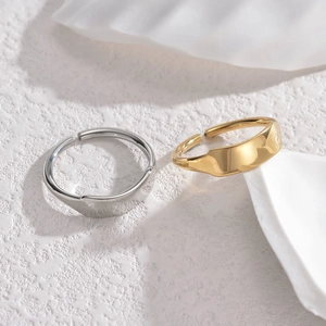 Minimalist irregular open rings in gold and silver finish on a textured white surface