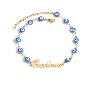 Detail of gold evil eye bracelet with blue beads and Precious lettering