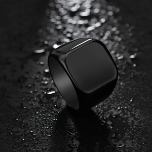 Minimalist black stainless steel signet ring for men on dark stone background