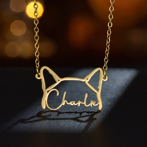 Custom dog silhouette necklace in gold finish with Charlie engraving on dark surface