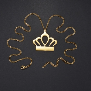 Collier avec pendentif couronne en acier inoxydable doré poli sur une surface noire mate