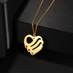 Golden heart pendant necklace with colorful gemstones on textured black jewelry box