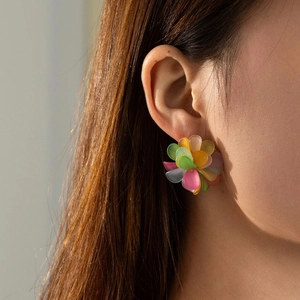 Gros plan d'un mannequin portant des boucles d'oreilles fleurs colorées au fini givré
