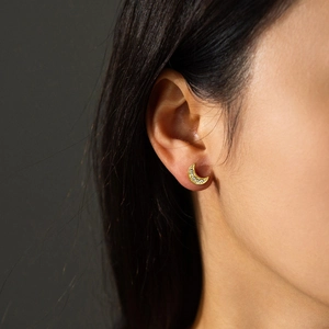 Close-up of golden crescent moon earring with white zircon stones on model's ear