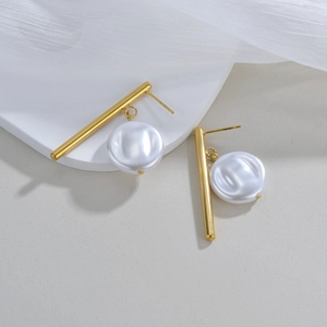 Minimalist gold stainless steel earrings with glossy flat pearl discs on white stone surface