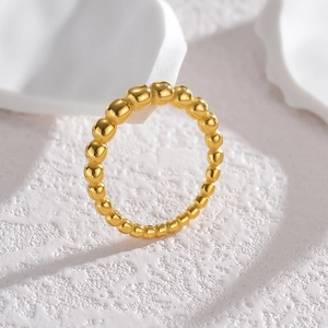 Minimalist gold beaded ring in polished stainless steel shown on textured stone background