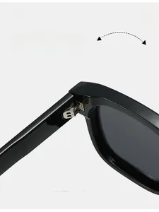 Détail de la charnière en métal argenté sur la monture de lunettes de soleil noire polie