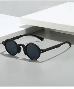 Detail of round retro sunglasses featuring gold rivet accents on black designer frames