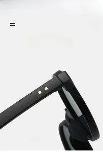 Close-up of matte black round frame glasses featuring gold rivet details on the hinges