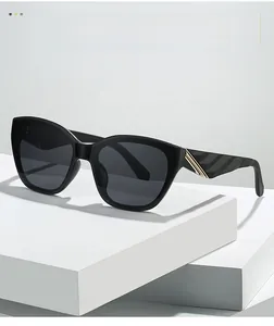 Detail of black cat-eye sunglasses with golden textured metal temples and dark lenses