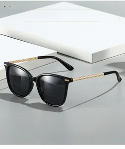Detailed view of black square sunglasses with gold textured metal temples and dark lenses