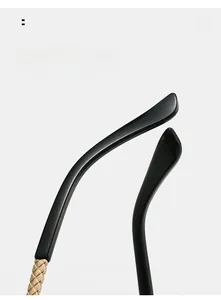 Detail of curved black sunglasses legs with gold woven texture metal hinges
