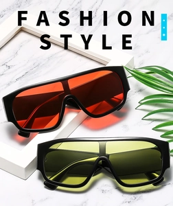 Flat lay of oversized shield sunglasses with red and yellow lenses on marble