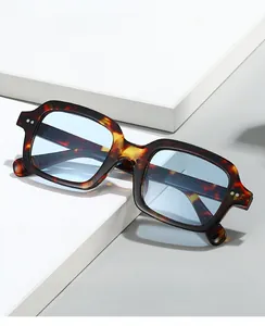 Detail view of tortoiseshell square sunglasses with blue lenses and decorative silver studs
